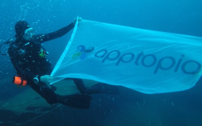 scuba diver holding apptopia flag underwater